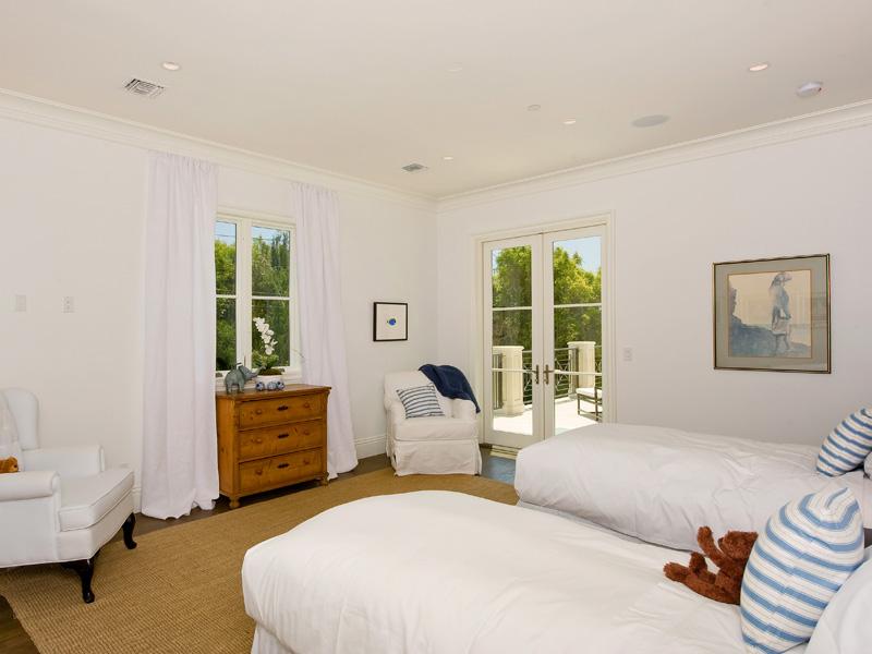 Bedroom with two twin beds with striped pillows, wood floor and a sisal rug