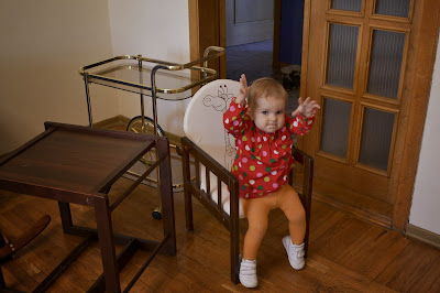 a small girl is sitting on the chair and playing in the living-room