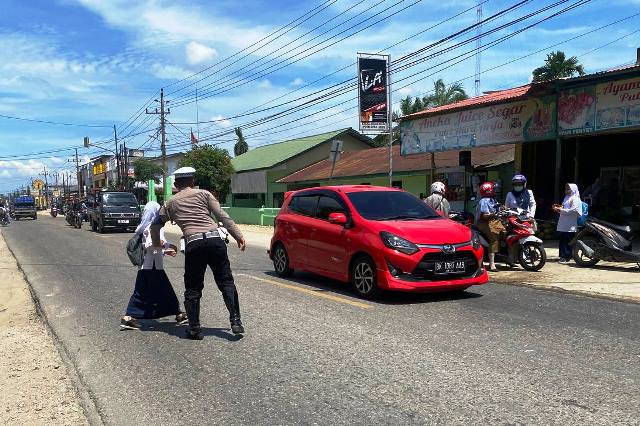 Gatur Lalin, Petugas Satlantas Polres Aceh Timur Bantu Seberangkan Anak Sekolah