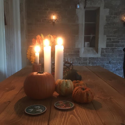 Pumpkins and lit candles on a wooden table in a stone room