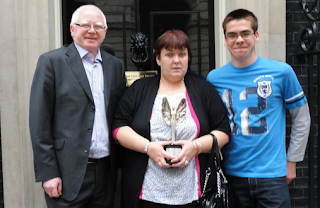 Image: Julie Coghill outside 10 Downing Street with her husband Philip and son Conor with her Pride of Britain Award. ©: courtesy of Philip Coghill