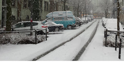 Snötäckt gata med bilar parkerade