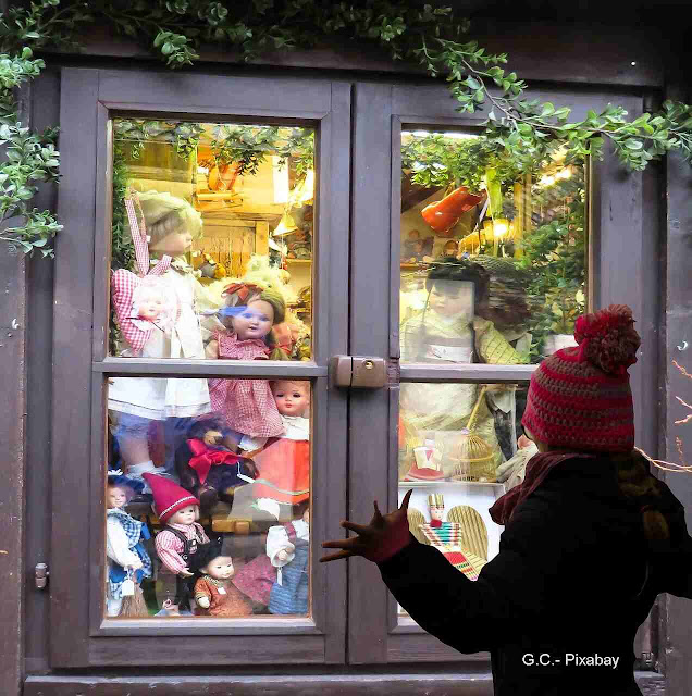 Criança olhando brinquedos em vidraça de janela.