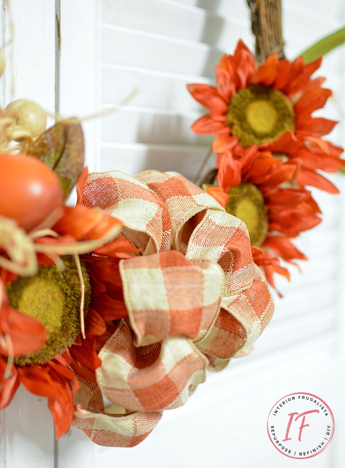 An easy orange sunflower fall wreath DIY idea in bright traditional autumn colors and a recycled grapevine wreath, a budget-friendly fall door wreath.