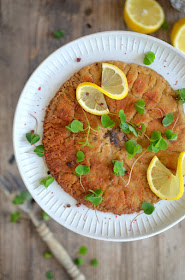 Goldgelb ausgebratenes Parasol-Schnitzerl auf einem Teller, mit Sauerklee und rosa Pfeffer bestreut und mit Zitronenscheiben garniert.