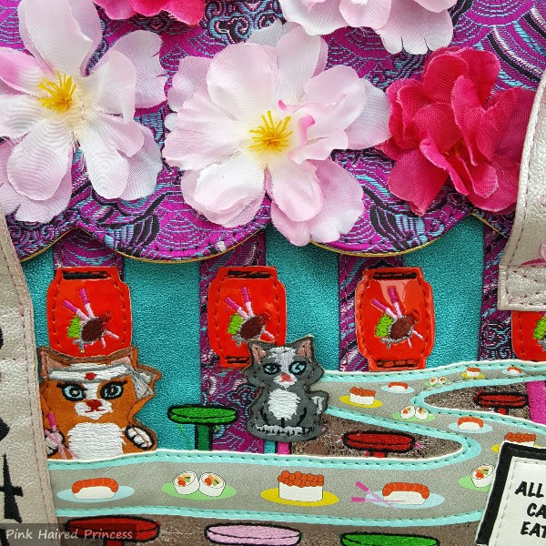 close up of sushi bar and cat applique with fabric flowers on flap of bag