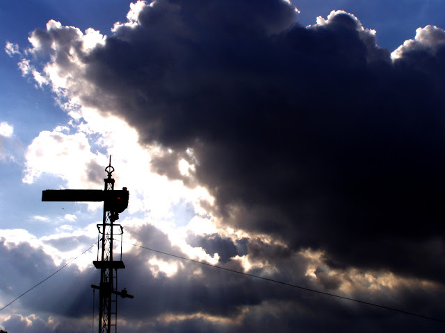 Dramatic Photo of semaphore railway signal standing out harshly against gathering dark storm clouds