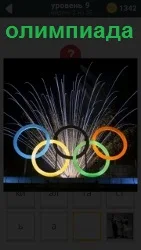 На фоне фейерверка кольца олимпиады, из - за которых фейерверк в разные стороны