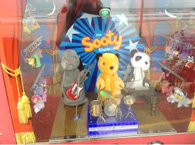 Sooty, Sweep and Soo playing music in an amusement arcade by the beach