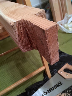 The end of a rough-cut rectangular tenon, still showing the pencil lines marking the edges. A large handsaw is visible at the bottom of the photo, with the "husky" logo very clear.