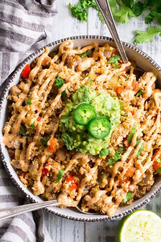 This Mexican Cauliflower Rice is packed with veggies, protein, and lots of flavor and spice! It's topped with an easy guacamole and chipotle ranch sauce for a tasty, filling meal that's Paleo