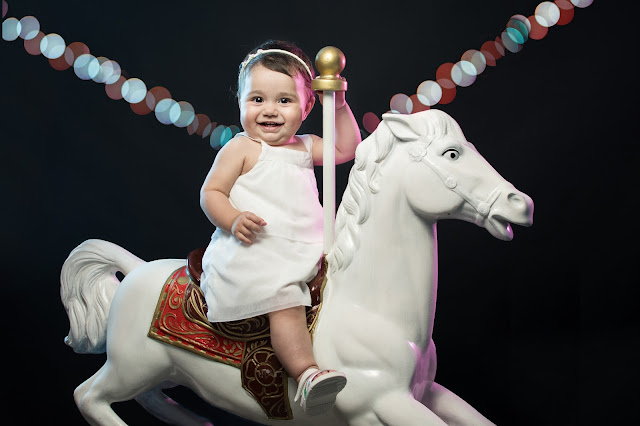 bebé feliz arriba de caballito de juguete de calesita, fotografía de estudio realizada en Roldán por Cristian Moriñigo