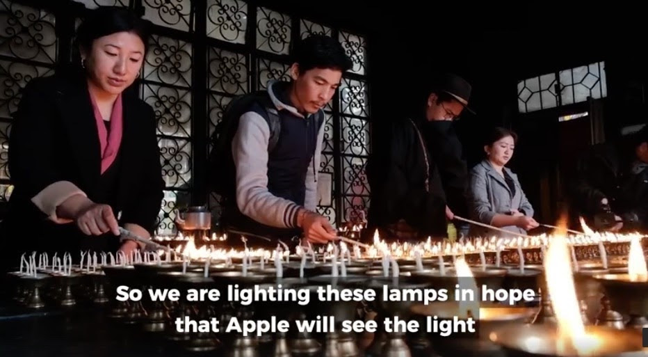 four people lighting butter lamps in a monastery in dharmsala with the captions we are lighting these lamps in hope that apple will see the light