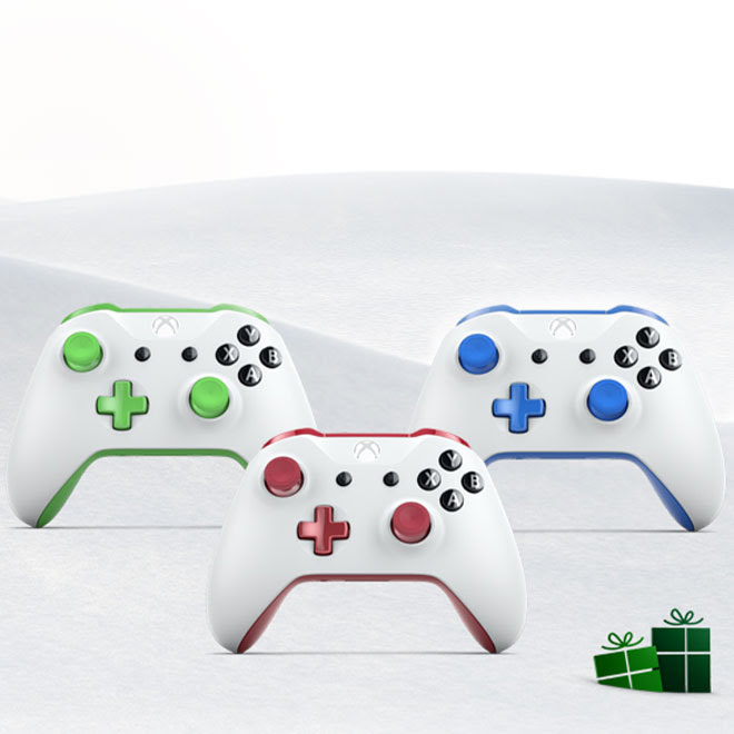 Against a holiday backdrop, three white Xbox One controllers each show a different color accent in green, red, and blue.