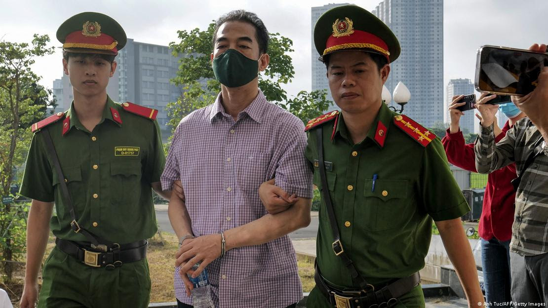 Vietnam's former Deputy Minister of Foreign Affairs Do Anh Dung being led into the court by police for his repatriation flight corruption trial in Hanoi on July 11, 2023
