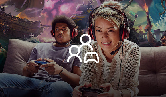 Two gamers sit side-by-side as they play each other with headsets on.