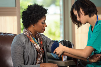 Health care worker setting up to take a woman’s blood pressure