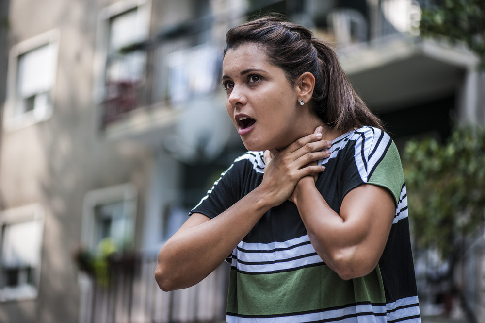 woman holding her throat as the sign for choking