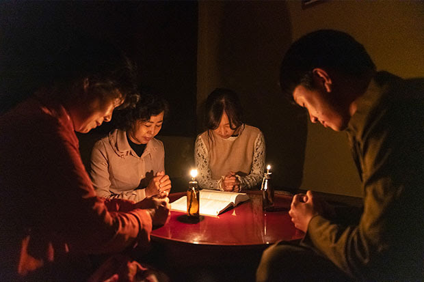 Family sitting around a table and praying