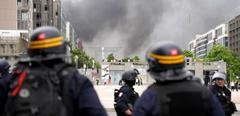 CRS riot police face protesters, with the "Grande Arche de la Defense" seen in the background, at the end of a commemoration march for a teenage driver shot dead by a policeman, in the Parisian suburb of Nanterre, on June 29, 2023. Violent protests broke out in France in the early hours of June 29, 2023, as anger grows over the police killing of a teenager, with security forces arresting 150 people in the chaos that saw balaclava-clad protesters burning cars and setting off fireworks. Nahel M., 17, was shot in the chest at point-blank range in Nanterre in the morning of June 27, 2023, in an incident that has reignited debate in France about police tactics long criticised by rights groups over the treatment of people in low-income suburbs, particularly ethnic minorities. (Photo by Zakaria ABDELKAFI / AFP)