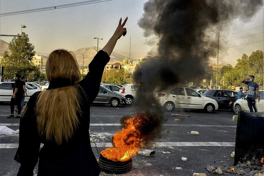 An unveiled woman, with her back to the camera, points two fingers as a sign of victory, during the protests in Iran.