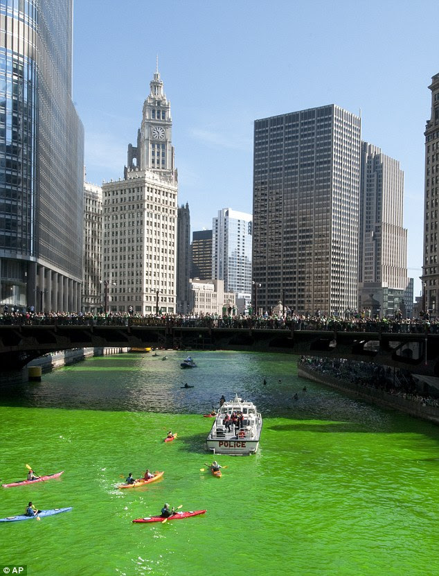 Eye catching: The river's dye drew thousands along its bank this morning, with a few kayakers paddling in the water, to get a glimpse of the bright green water