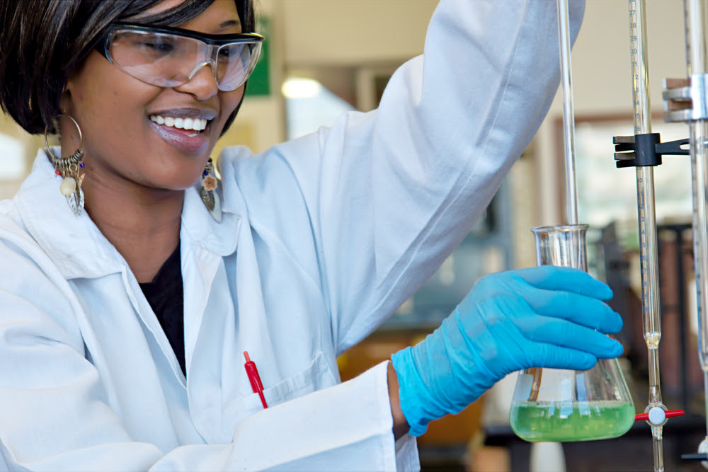 smiling black woman scientist measuring liquid in a laboratory setting