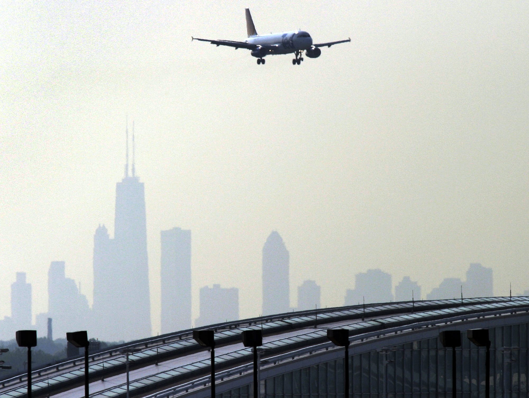 The Chicago skyline is silhouetted in the background as a plane descends comes in to land at O'Hare International Airport on July 15, 2004.