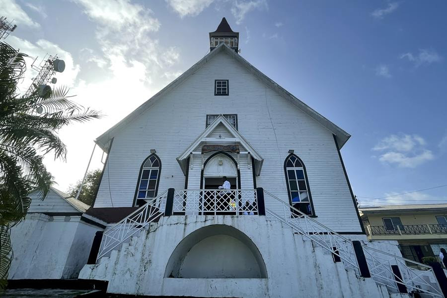 A man stands at the entrance of First Baptist Church on Colombia's San Andres Island. The church is painted white and the windows are outlined in black.