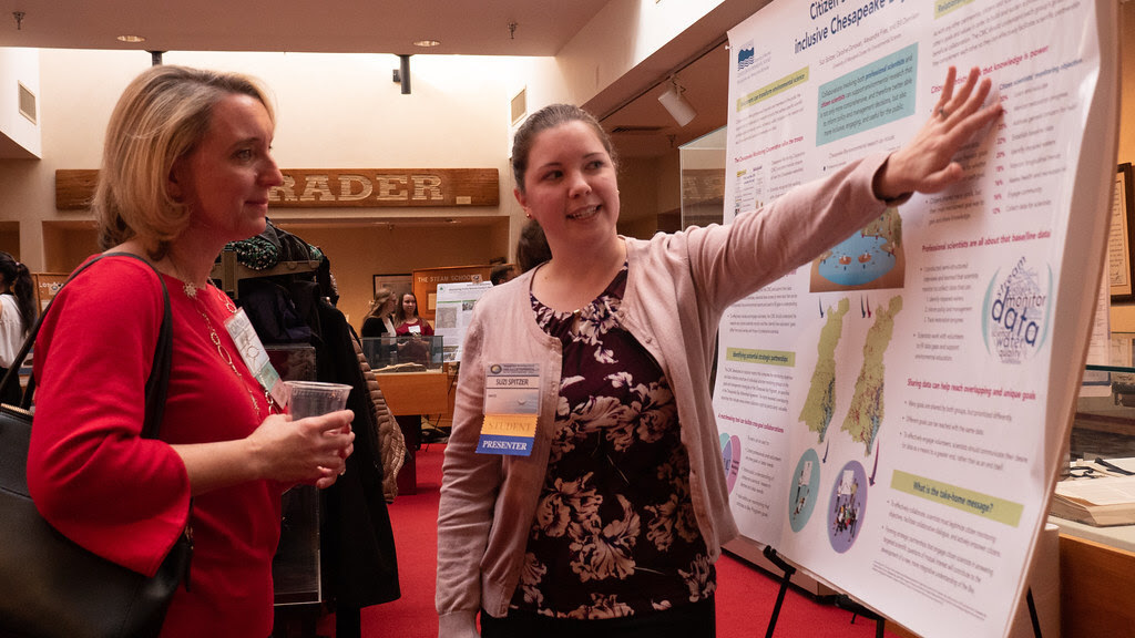 Photo of woman demonstrating scientific information on a poster