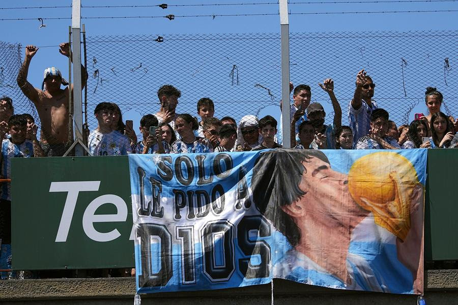 A painted poster shows a man kissing a soccer ball and reads "Solo le pido a dios"