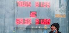 A man walks past a board showing currency exchange rates of the US dollar and the euro against Russian ruble in Moscow on February 22, 2022. - Russian stock indexes fell sharply Tuesday morning, after Moscow recognised the independence of Ukraine's two separatist regions and President Vladimir Putin sent troops into the Western-backed country. The dollar-denominated RTS index was down 10.8 percent at 0713 GMT, and 32.5 percent since the start of the year. The ruble-based MOEX fell by 8.8 percent. The Russian currency also slid, with the ruble trading at more than 91 to the euro and 80.7 to the dollar. (Photo by Dimitar DILKOFF / AFP)