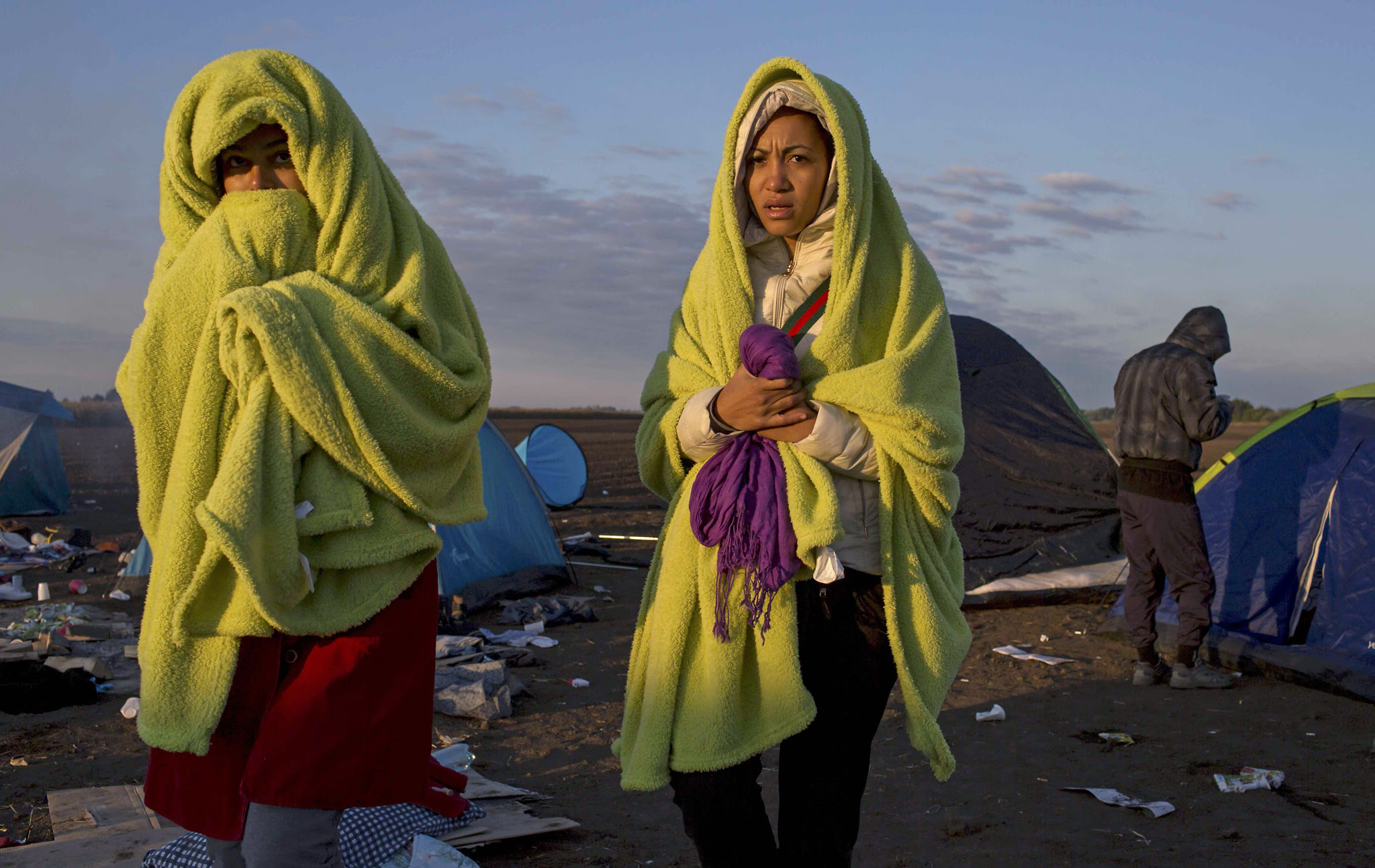 Migrants wrap themselves in blankets to warm up as the sun rises at a collection point in the village of Roszke...Migrants wrap themselves in blankets to warm up as the sun rises at a collection point in the village of Roszke, Hungary September 9, 2015. REUTERS/Marko Djurica