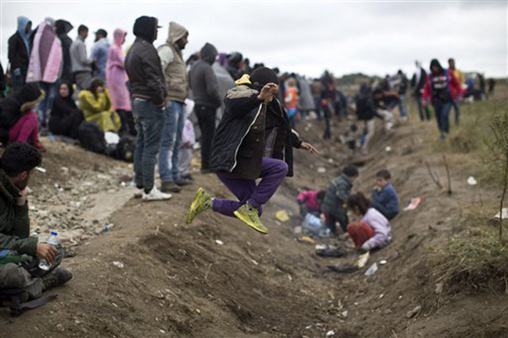 A child jumps over a ditch as people wait in order to clear a police line after entering Croatia from Serbia in Strosinci, Croatia, Saturday, Sept. 26, 2015. Conciliation replaced confrontation among European nations which have clashed over their response to a wave of migration, but confusion faced many asylum-seekers streaming into Croatia on Saturday in hopes of chasing a new future in Western Europe. Photo: MARKO DROBNJAKOVIC — AP Photo