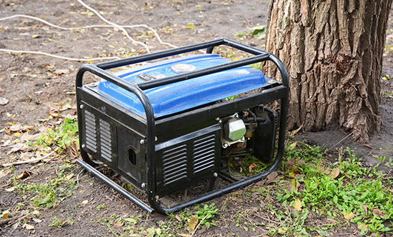 A portable generator placed outside and in a dry area on the ground.