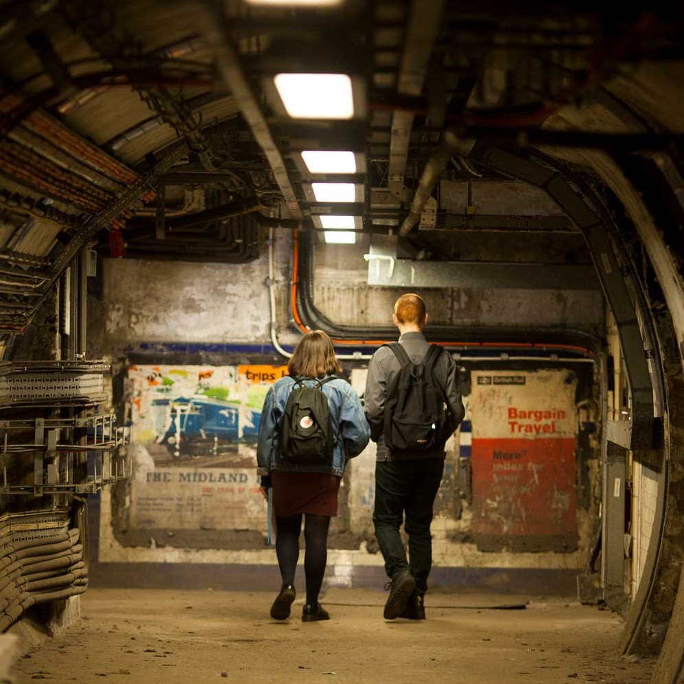 Two people looking at posters in Euston station