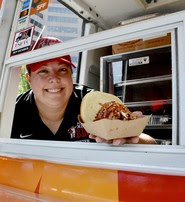 Owner of Sweets and Meats, Kristen Bailey holding a pulled pork taco in her food truck