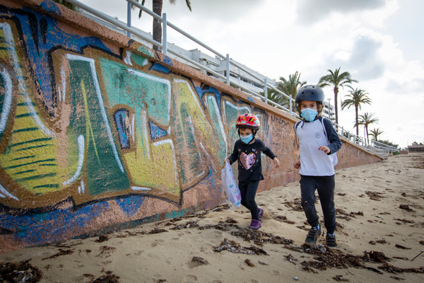 Two children wearing face masks play on Portixol Beach in Palma de Mallorca, on April 26, 2020 during a national lockdown.