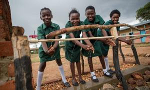 Alumnos se limpian las manos en un punto de lavado de manos recién construido en una escuela primaria del distrito de Pemba, Zambia.