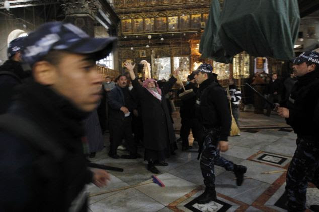 Skirmish: A member from the Armenian clergy raises his arms as Palestinian police officers try to restore order at the Church of Nativity