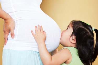 child kissing mothers pregnant belly