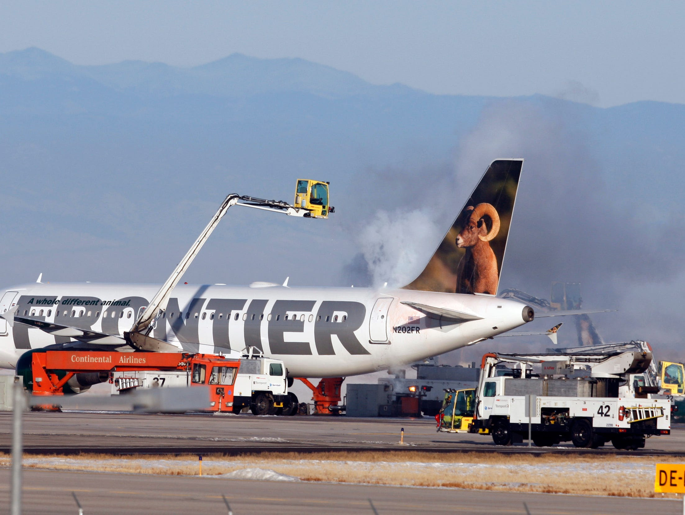 A Frontier Airlines jetliner is sprayed with de-icing fluid before taking off from Denver International Airport.
