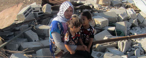 Khadijeh Bsharat and her daughters on the ruins of her home. Photo: ‘Aref Daraghmeh, B’Tselem, 27 August 2015