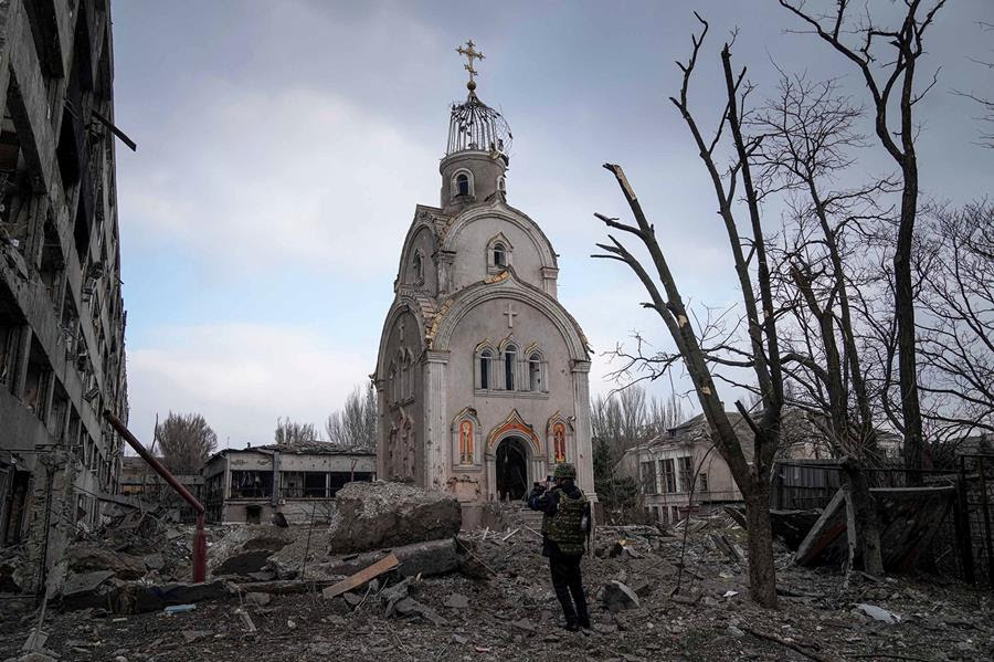 A Ukrainian serviceman takes a photograph of a damaged church after shelling in a residential district in Mariupol, Ukraine. Part of the church is still standing.