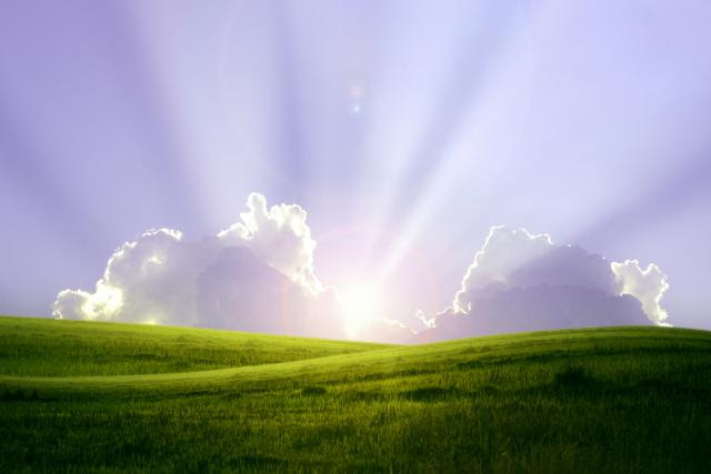 Green fields with sun shining through clouds