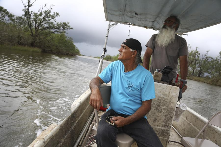 Donald Dardar, left, and Russell Dardar look toward the eroding shoreline of Bayou Pointe-au-Chien in southern Louisiana on Wednesday, Sept. 29, 2021. The brothers have lived along the bayou all their lives as shrimpers and fishermen. They now also work to preserve the coastal land from further erosion by refilling canals and developing living shorelines. (AP Photo/Jessie Wardarski)