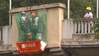 Operaris treballant per treure els escuts amb àguiles franquistes del pont de l'Aigua aquest dilluns a Girona