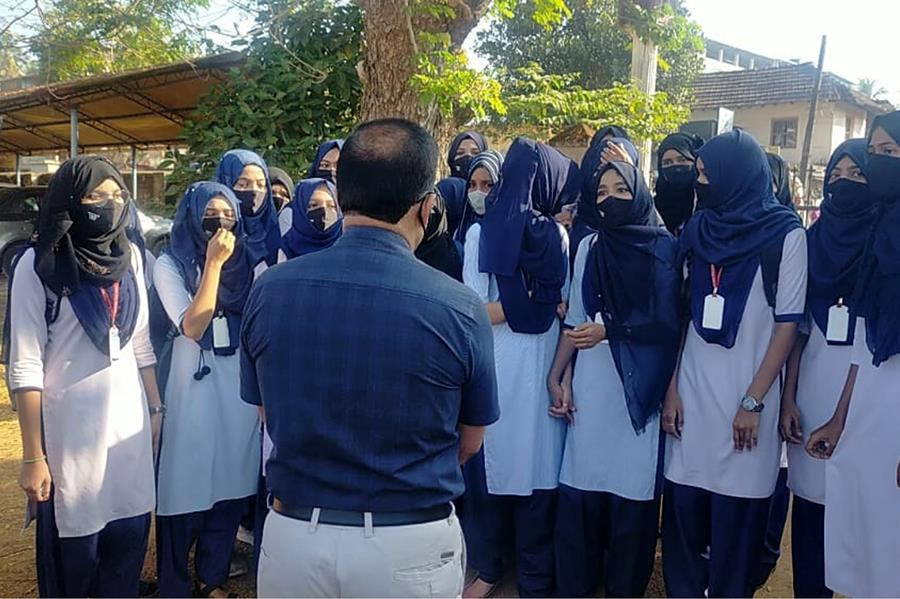 Indian girl students who were barred from entering their classrooms for wearing hijab, a headscarf used by Muslim women, speak to their principal outside the college campus in Udupi, India, Friday, Feb. 4, 2022.
