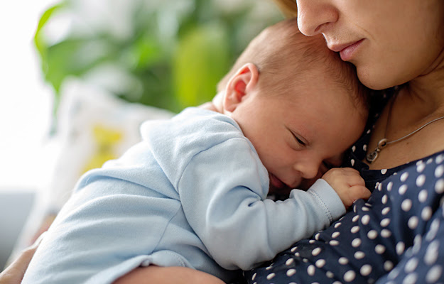 A baby lying on its mother's chest.