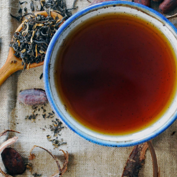 Cup of tea and a wooden spoon full of tea leafs